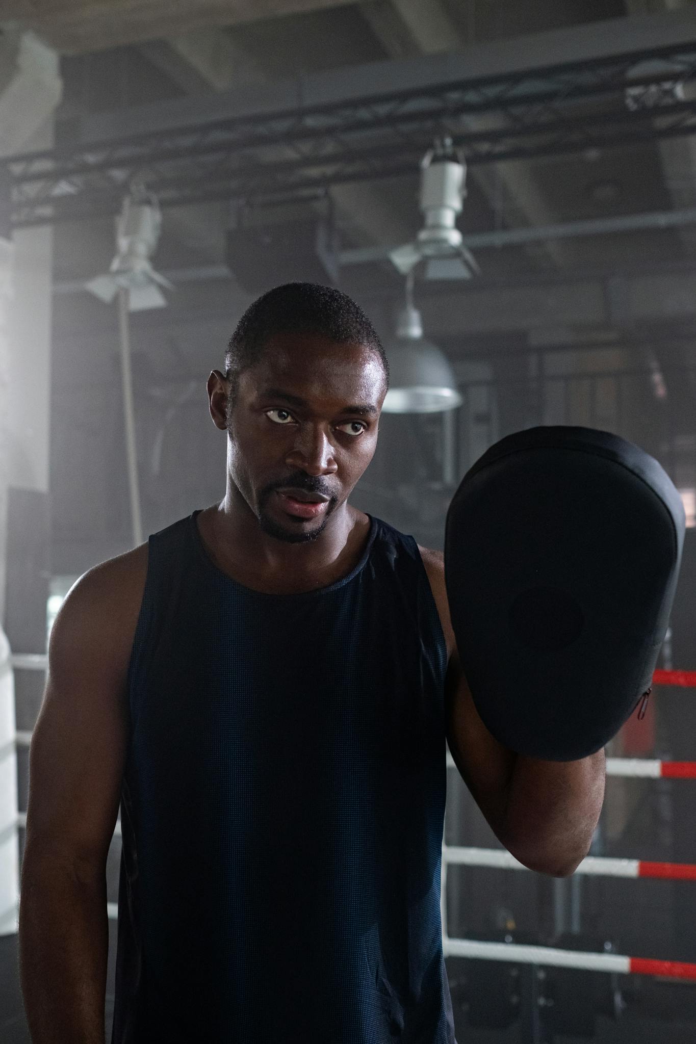 A dedicated boxing trainer holding a pad during a gym session.