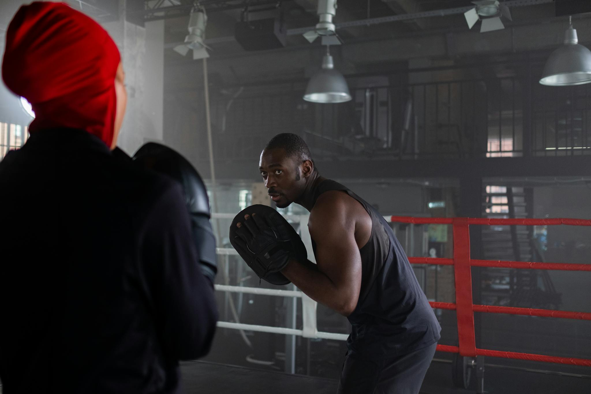 Focused boxing workout in a gym setting with trainer guidance.